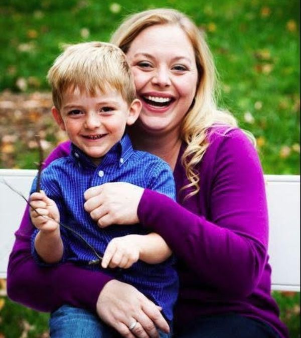 Courtney Bugler kneels on the ground, cuddling with her young son.