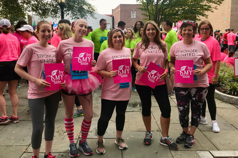 Caroline Abi-Khattar smiling in pink with other breast cancer survivors