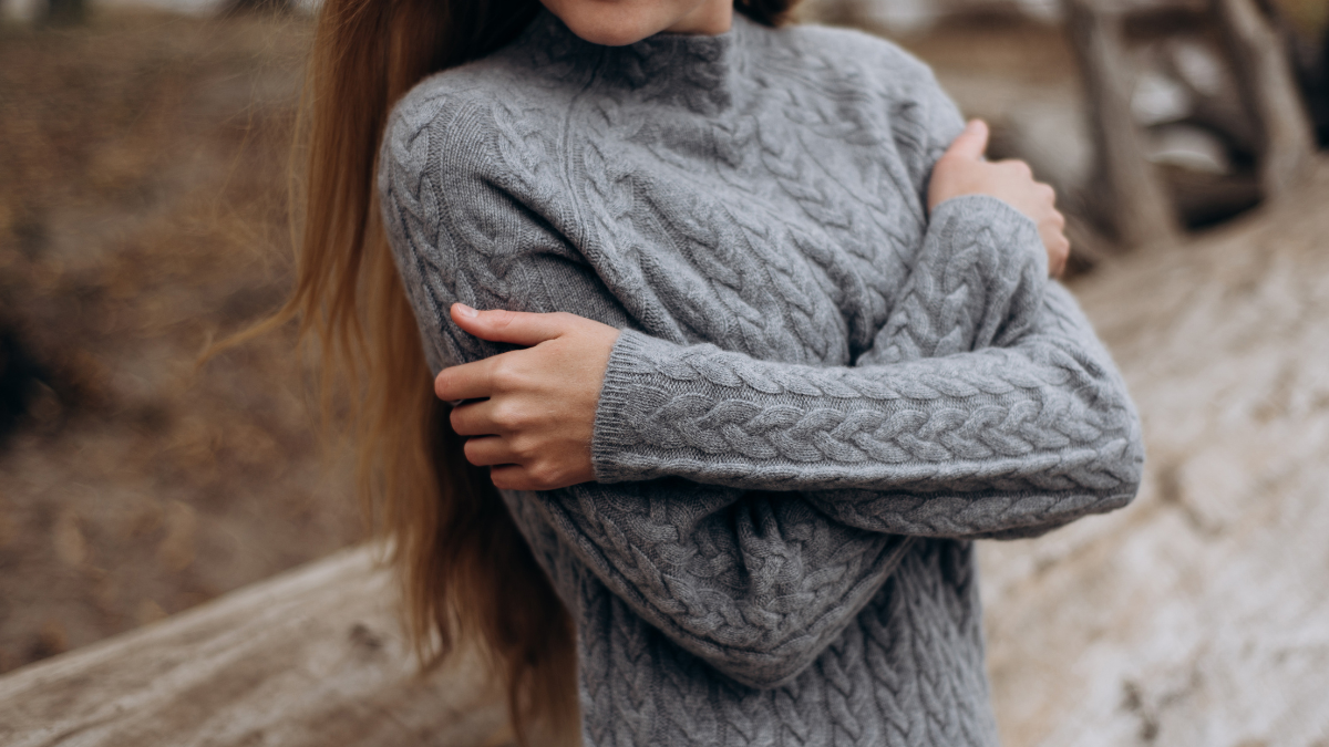 A white woman wearing a grey cable-knit cashmere sweater