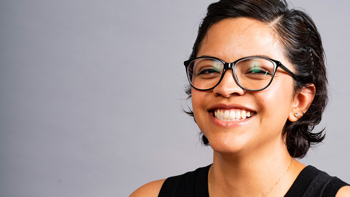 An Asian woman smiling in front of a grey background