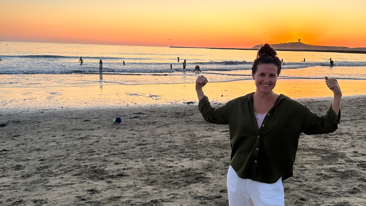 Nicole Beck smiling on the beach in front of the sunset