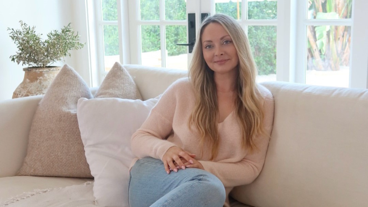 Chloe sitting in her living room on a white couch