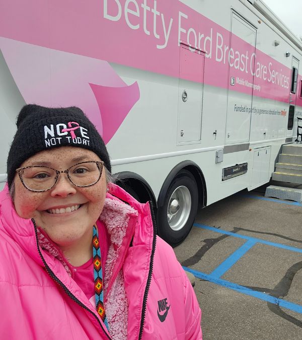 Lisa Walker stands proudly in front of the mobile mammography bus she helped bring to her community to get more women screened for breast cancer.