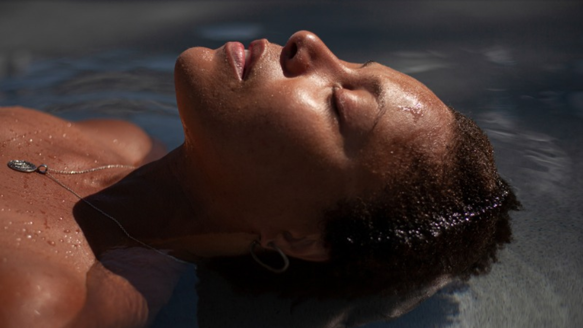 Blogger Kia Lee floating with her eyes closed in a shallow pool of water.