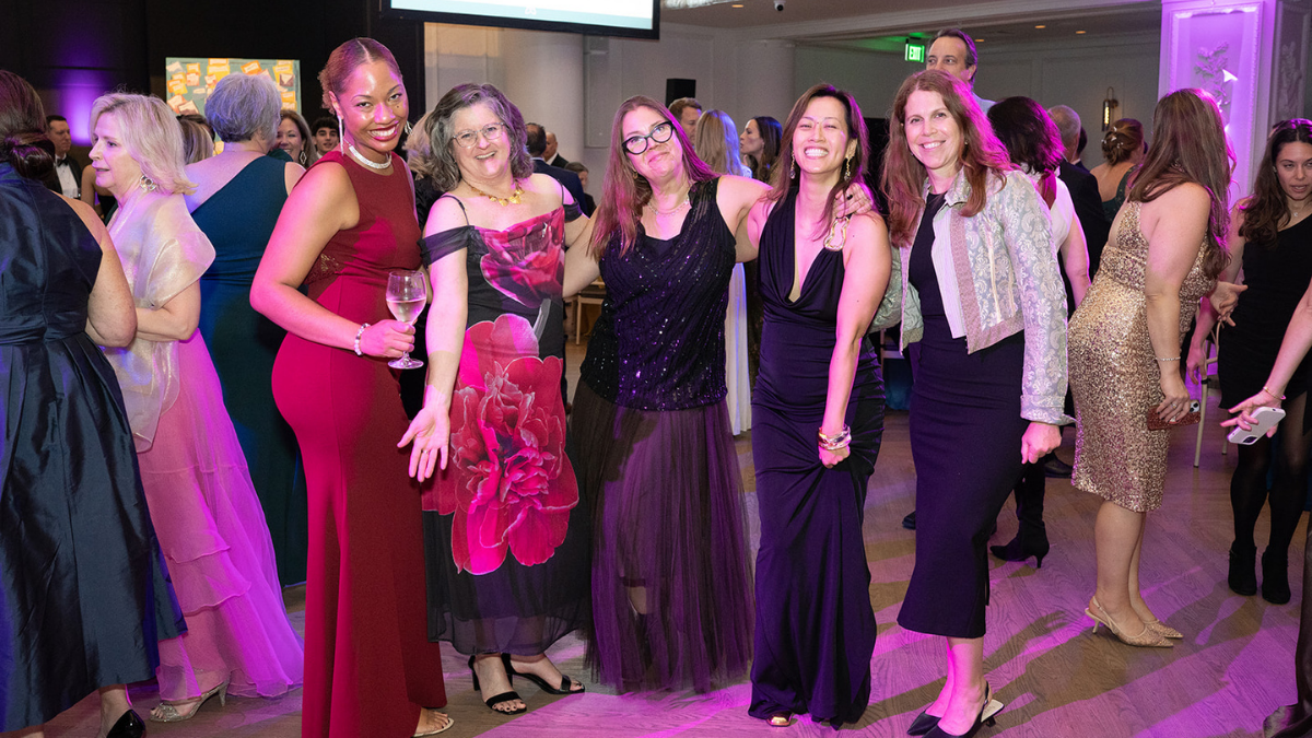 A diverse group of women smiling and dancing on the dance floor