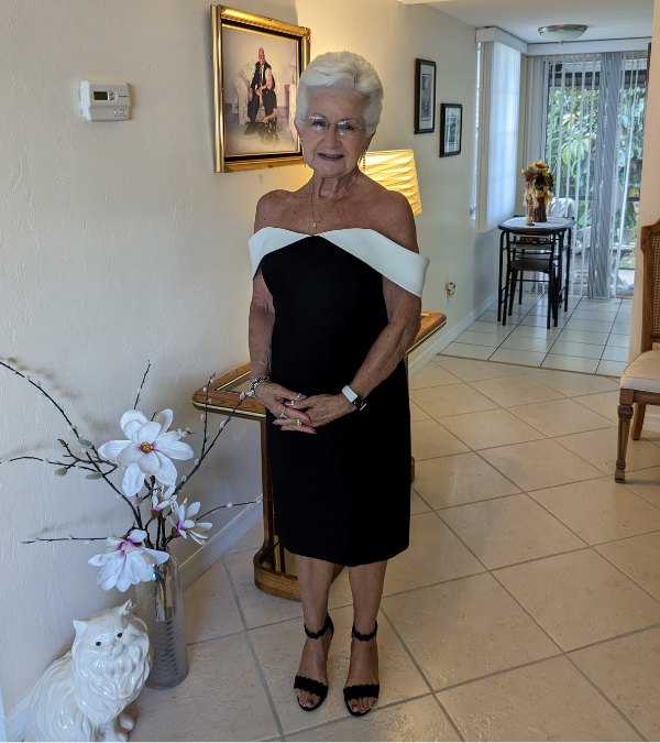 Myra smiling in her house in a black and white dress