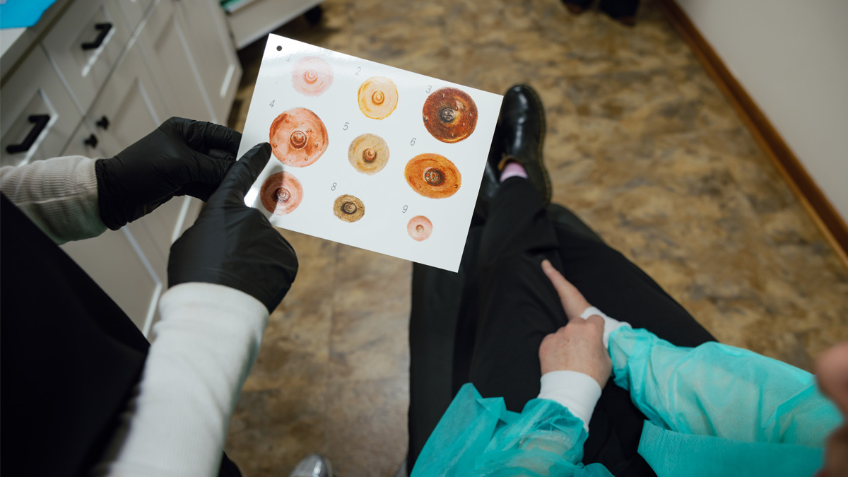 Paramedical tattoo artist shows 3D nipple examples to breast cancer patient.