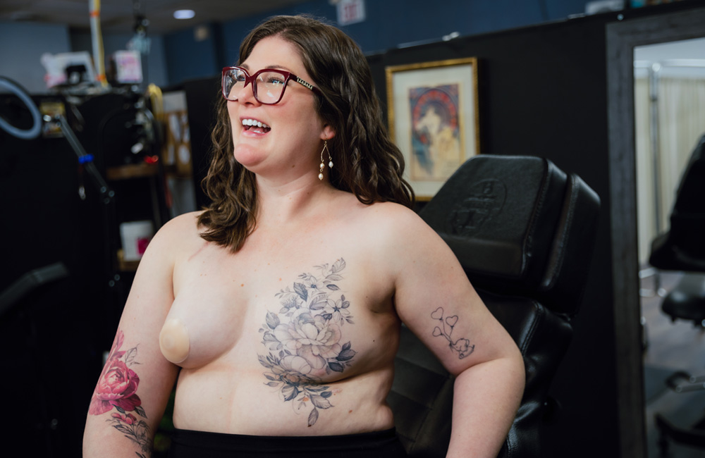 Woman laughing and showing post-mastectomy tattoo after breast cancer