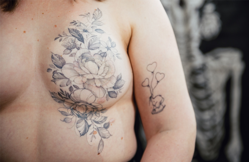 Fine line tattoo of flowers over post-mastectomy scars.