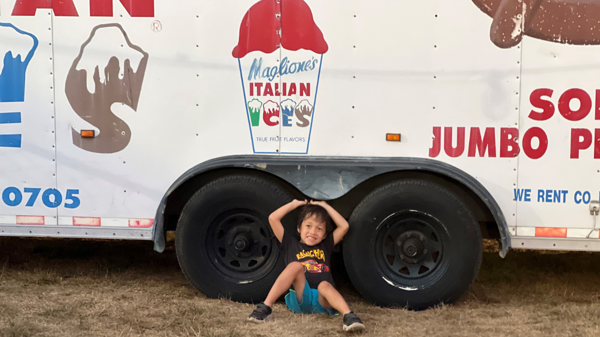 Jenny Peterson's son sitting in between the tires of an ice cream truck