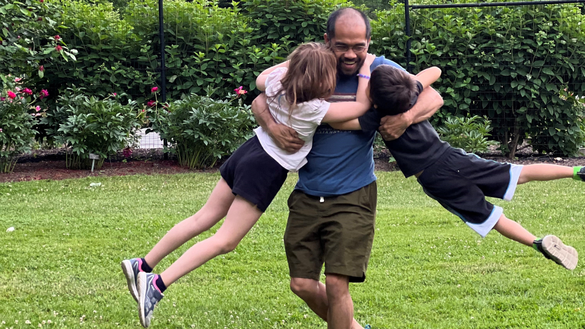 Jenny Peterson's husband holding their two youngest children and spinning them around outside