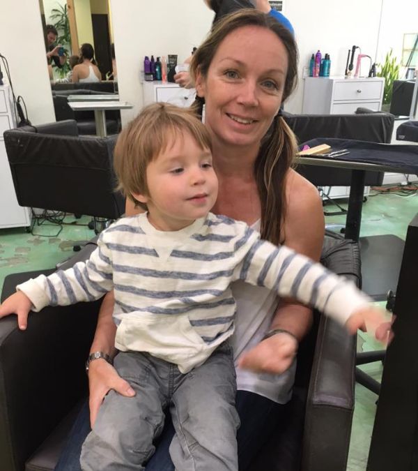 Silvia Gogh and her young son (who sits on her lap) await a haircutting appointment in the stylist shop.