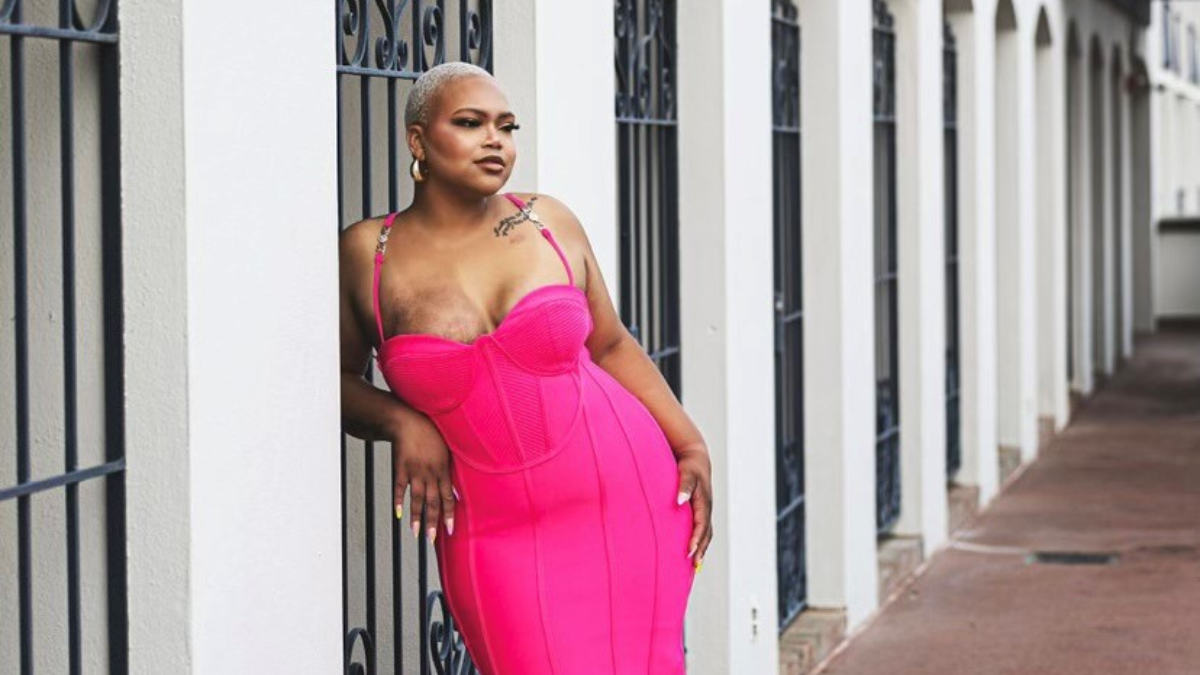 Tiana Russell in a bright pink dress leaning against a wall