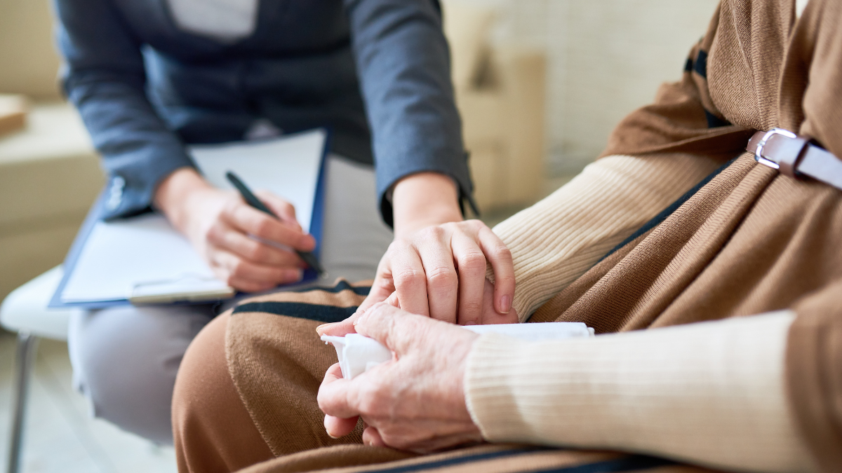 A close-up image of a person holding a tissue and another person holding their hand.