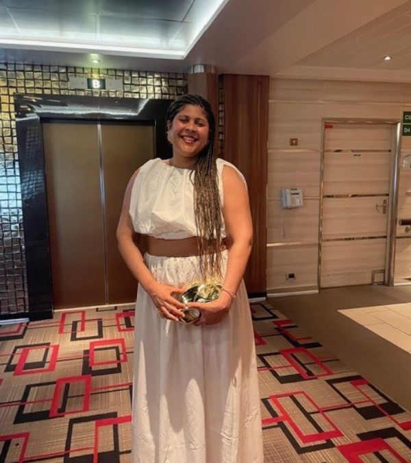Amara Brown wears a comfortable but stylish, white gauze, two-piece, midriff-baring outfit.
