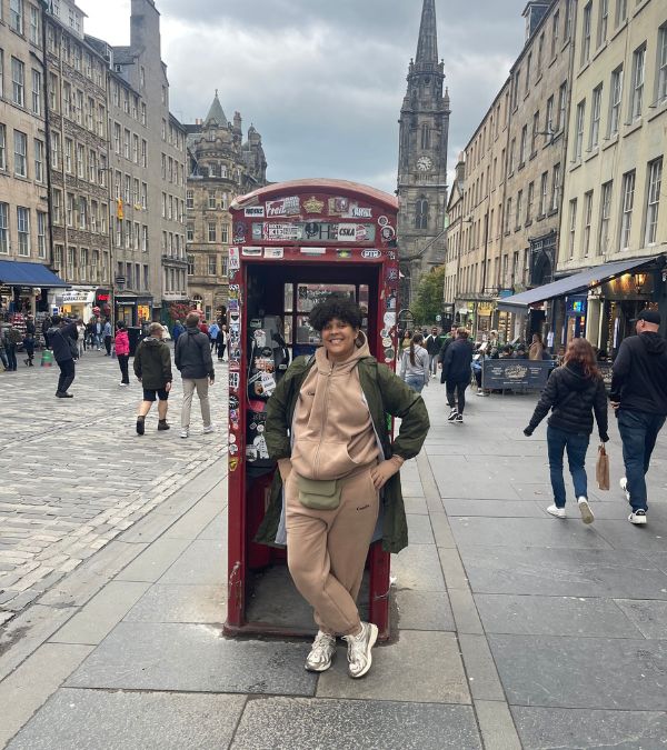 Amara Brown stands in an iconic red phone booth in the United Kingdom.