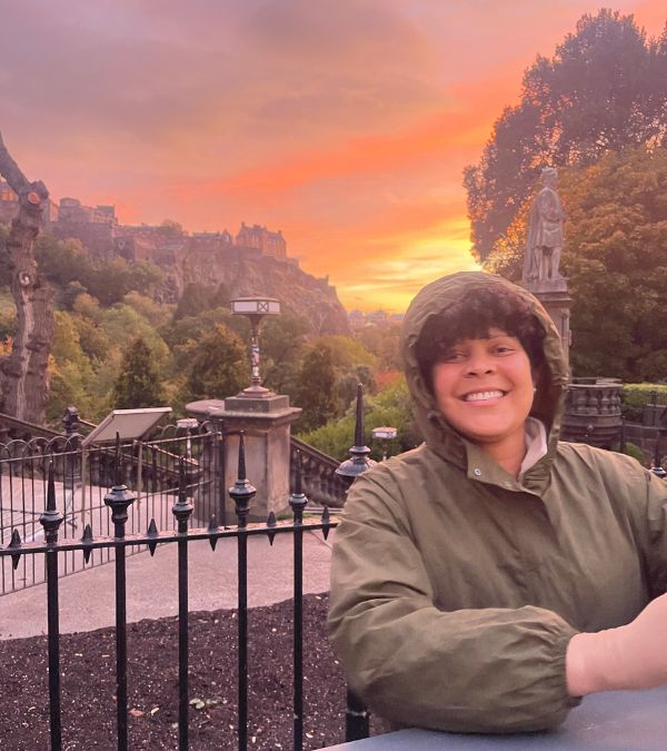 Amara Brown's smile beams brighter than the setting sun, with many beautiful pinks, oranges and yellows, behind her.