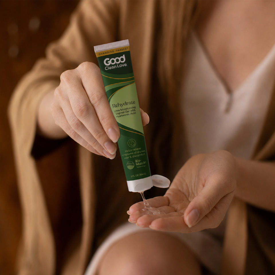 A woman holding a thin green tube of moisturizing vaginal gel