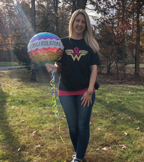 Jessica Fioretti poses wearing a Wonder Woman t-shirt and holding a mylar balloon that reads, "Congratulations."