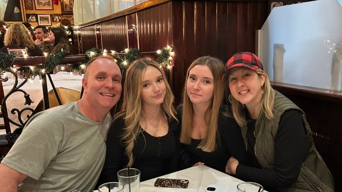Jessica Fioretti sitting at a restaurant table with her husband and two daughters.