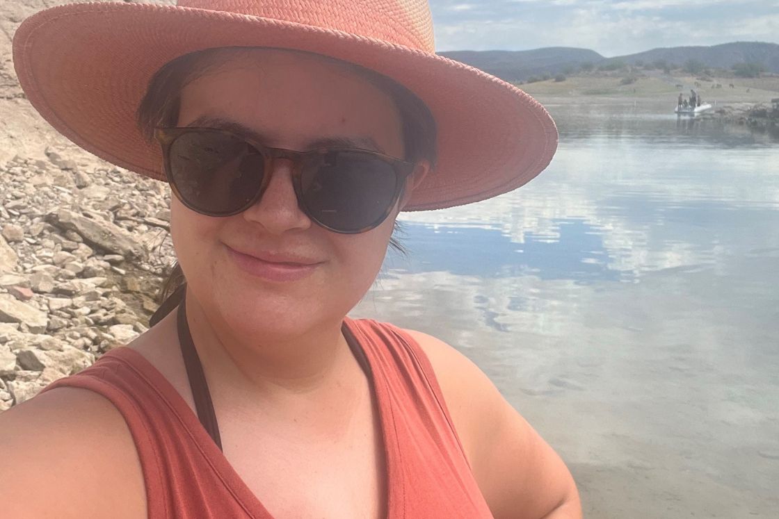 Kyla Wenger wears a brimmed hat in front of a pretty lake.