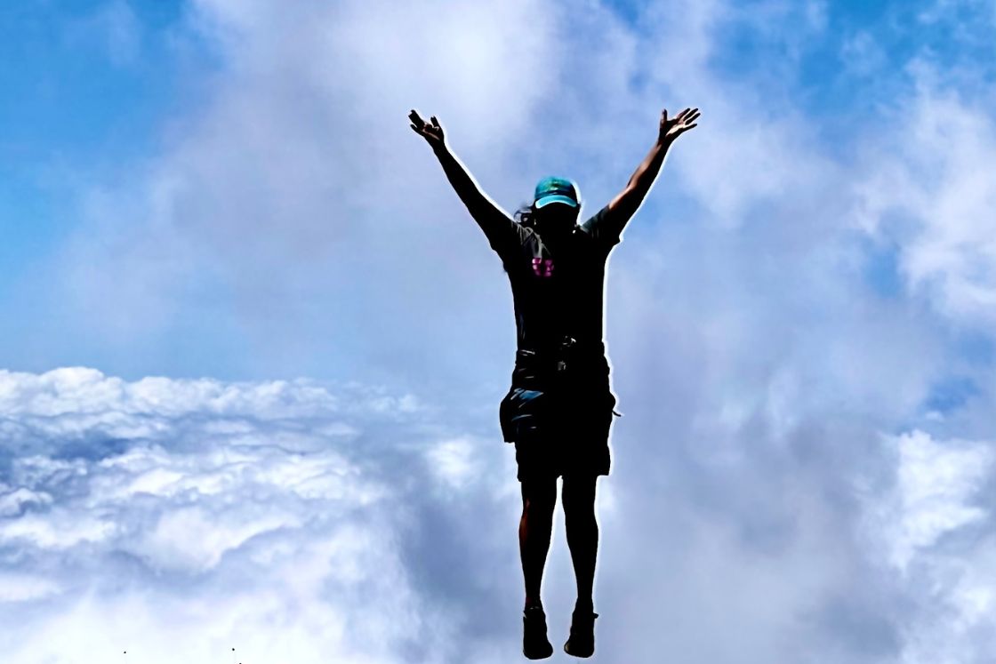 Tiernnee' Jefferis ijumps, silhouetted against a high mountain cloud.