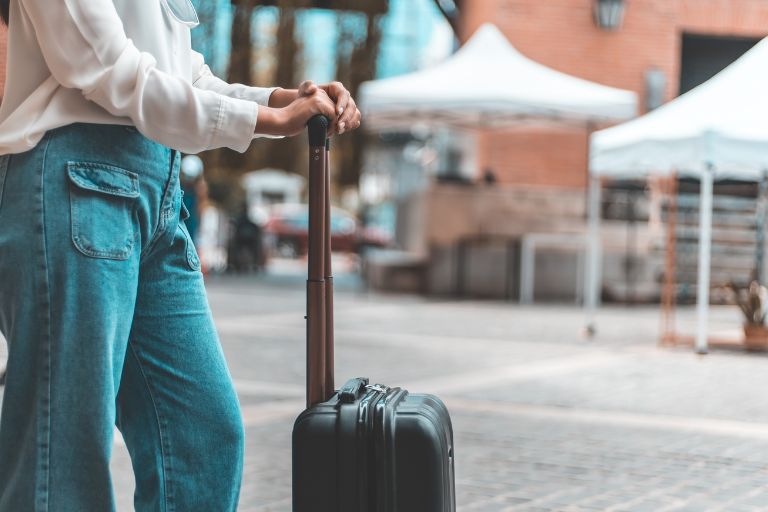 A woman leans on her suitcase as she examines the festival scene ahead.