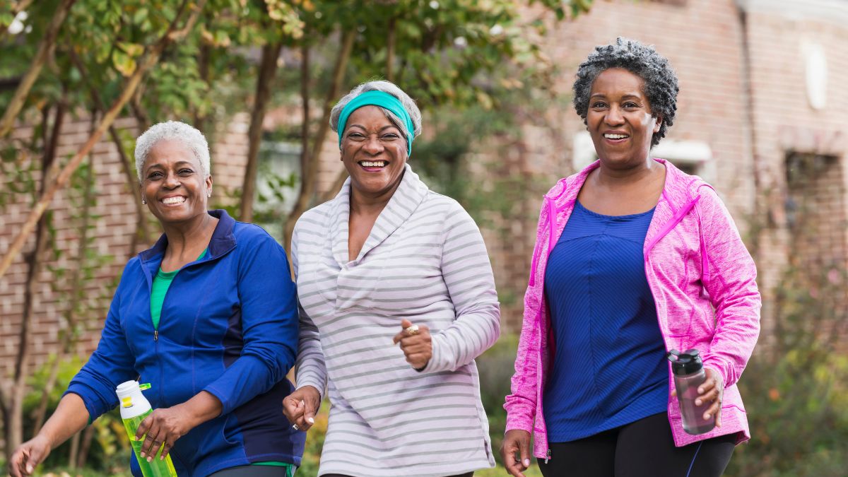 3 older Black woman smiling on a walk outside