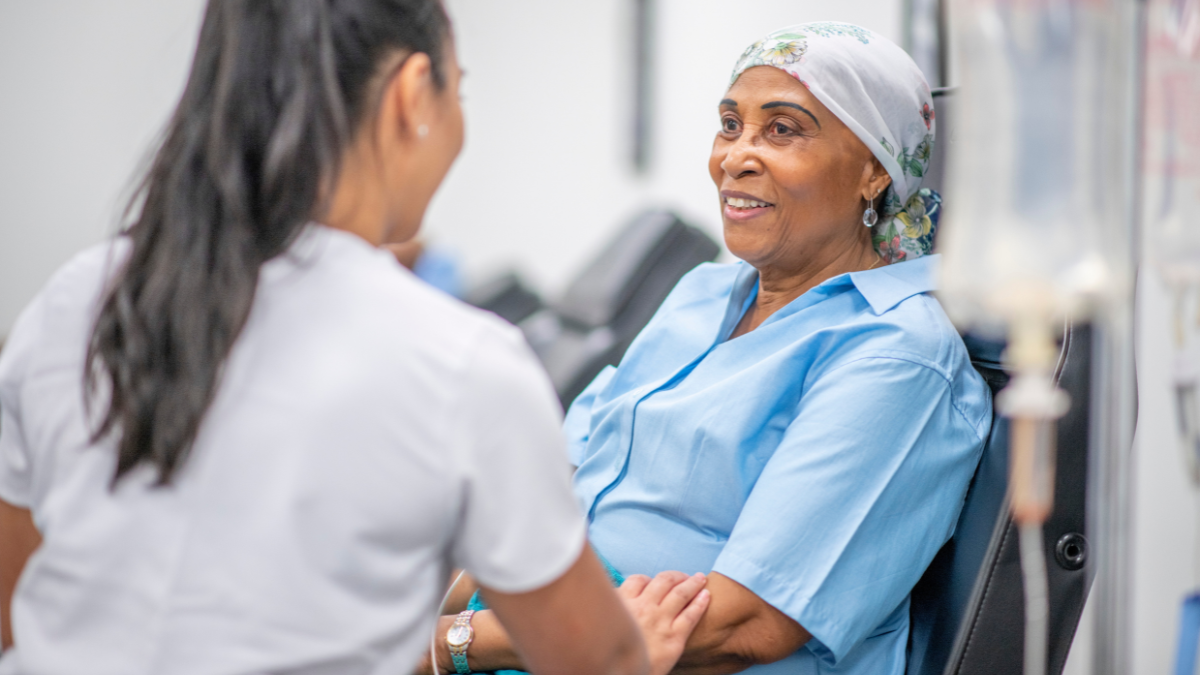 A Black woman smiling, talking to her doctor