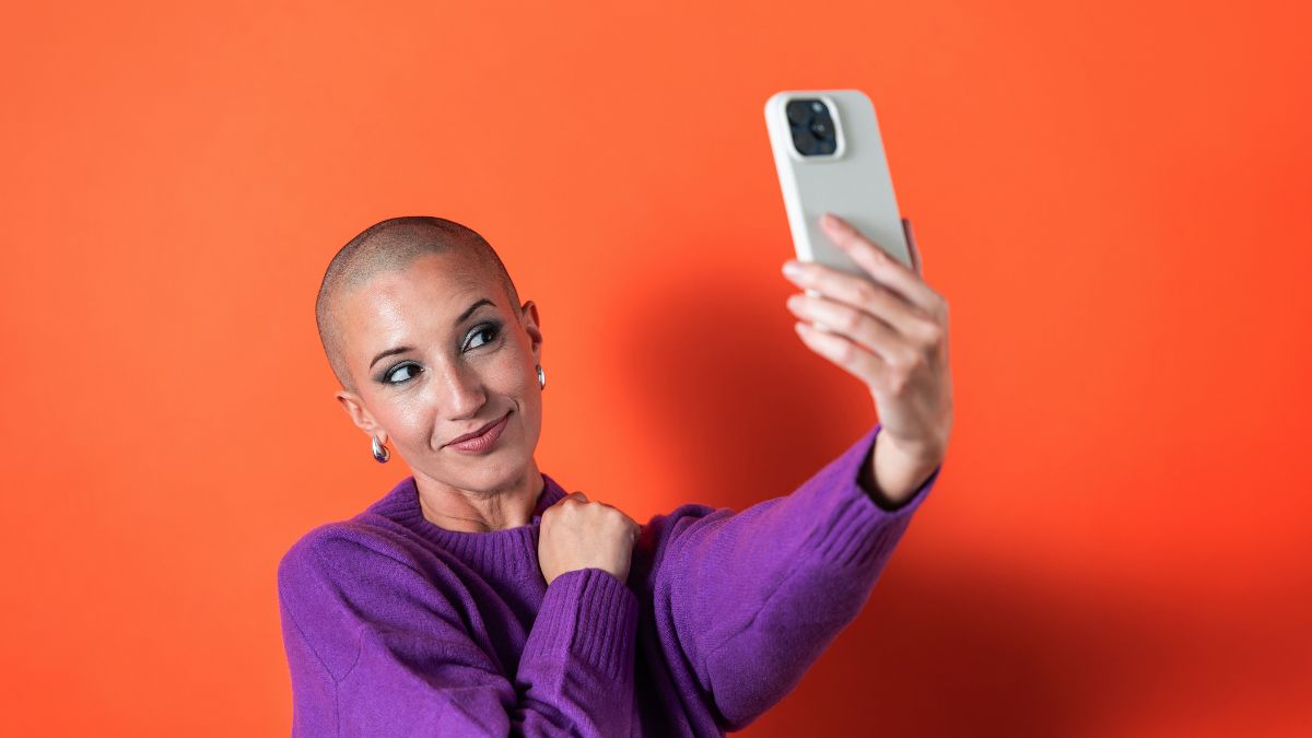 A bald young woman taking a selfie