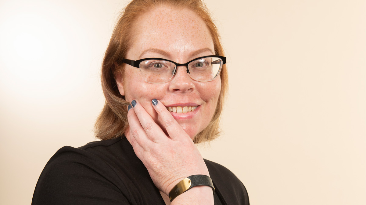 A white woman with MBC smiling, posing with her hand on her face