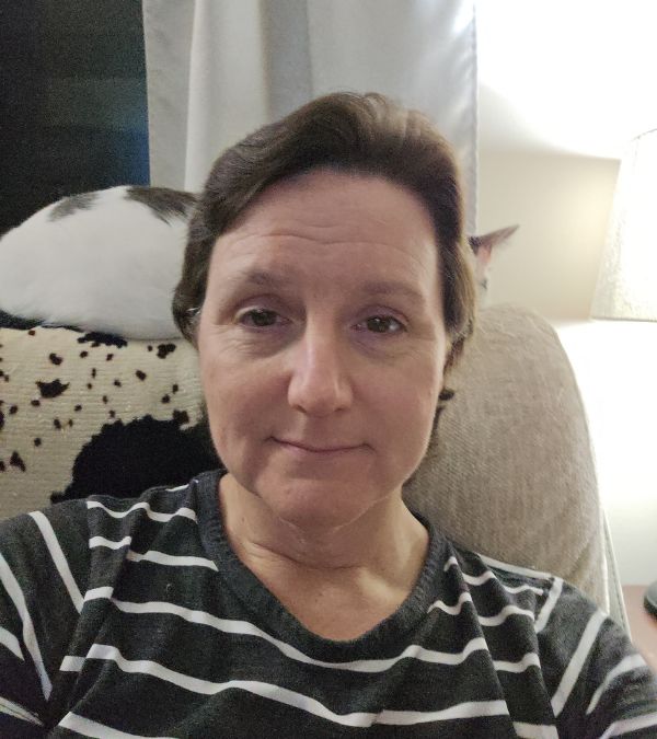 Ericka Toth sits on her sofa wearing a striped top.