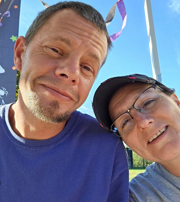 A smiling Ericka Toth rests her head on her husband's shoulder.