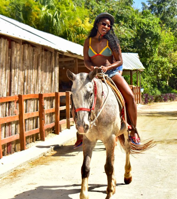 Nikki Taylor rides a horse on a sun-drenched trail.