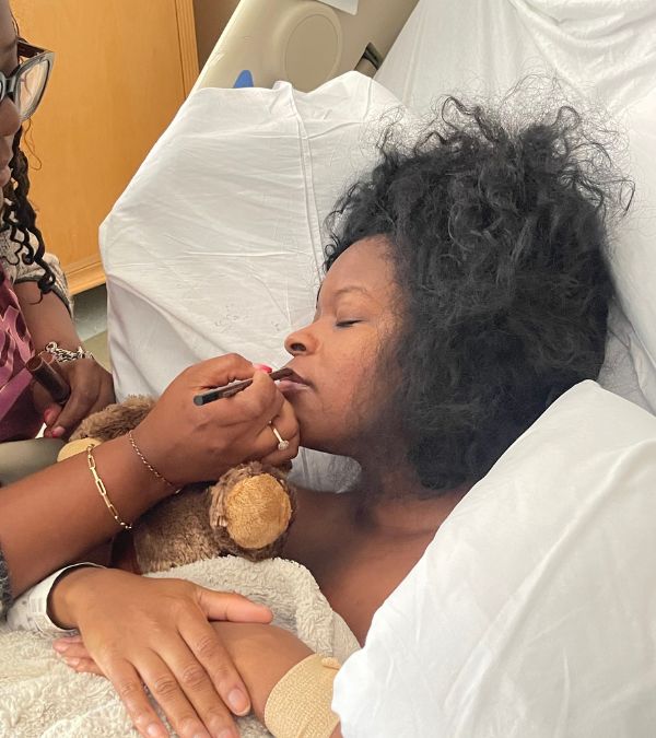 Someone applies lipstick to Nikki Taylor, who recovers from surgery in her hospital bed.