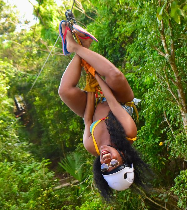 Nikki Taylor hangs upside down on a zipline during a tropical vacation.