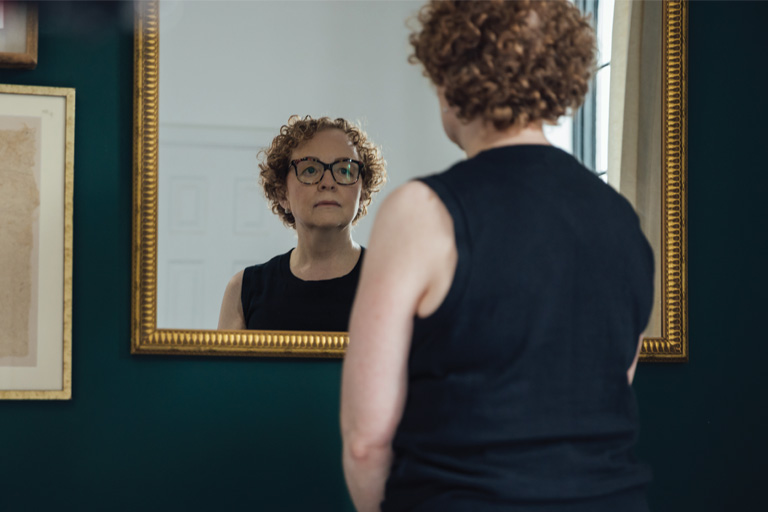 A white woman staring at herself in a mirror