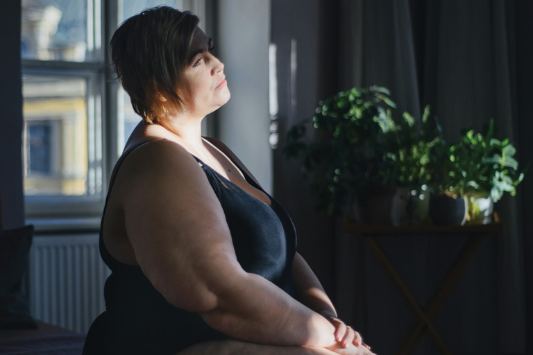 A larger white woman sitting, staring in the distance