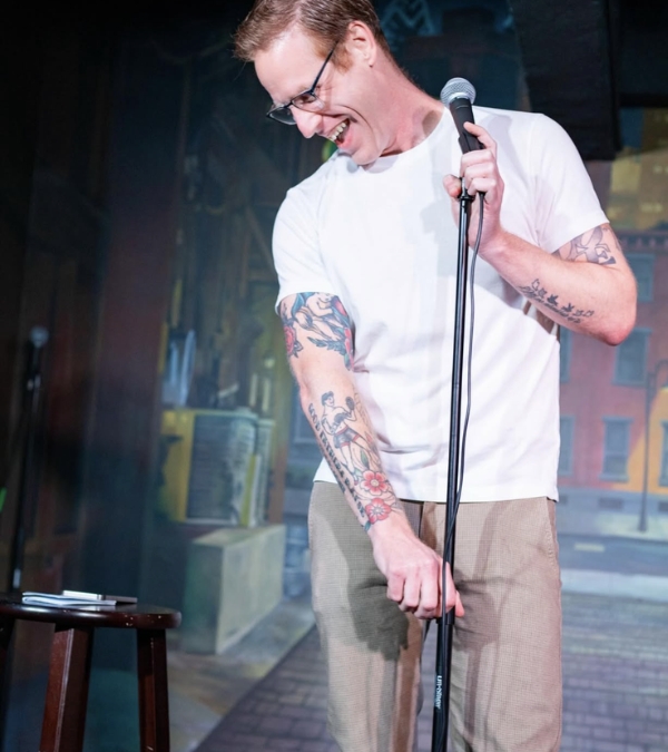 Dave Bohannon performing stand up, holding a microphone on stage.