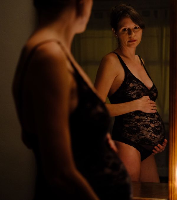 Kim Quick regards herself in the mirror wearing a lace body suit before her mastectomy.