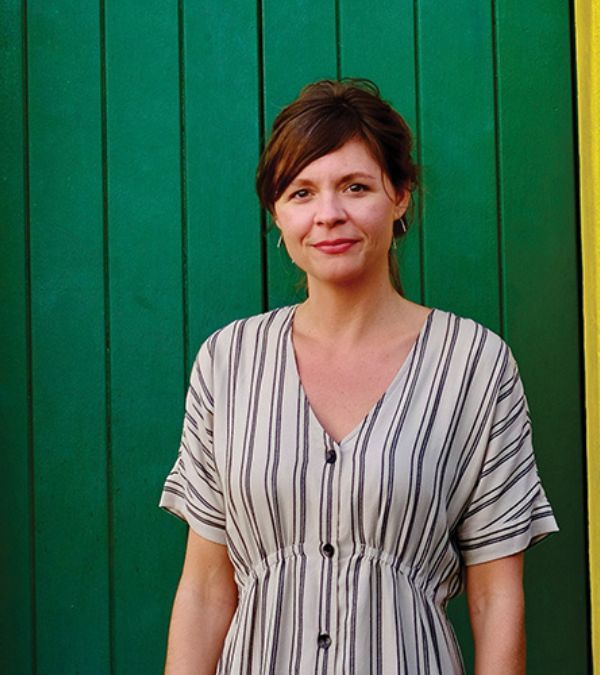 Kim Quick stands before a kelly green background.