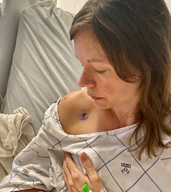 Lying in a hospital bed, Kim Quick looks at a mark made on her shoulder before her mastectomy.