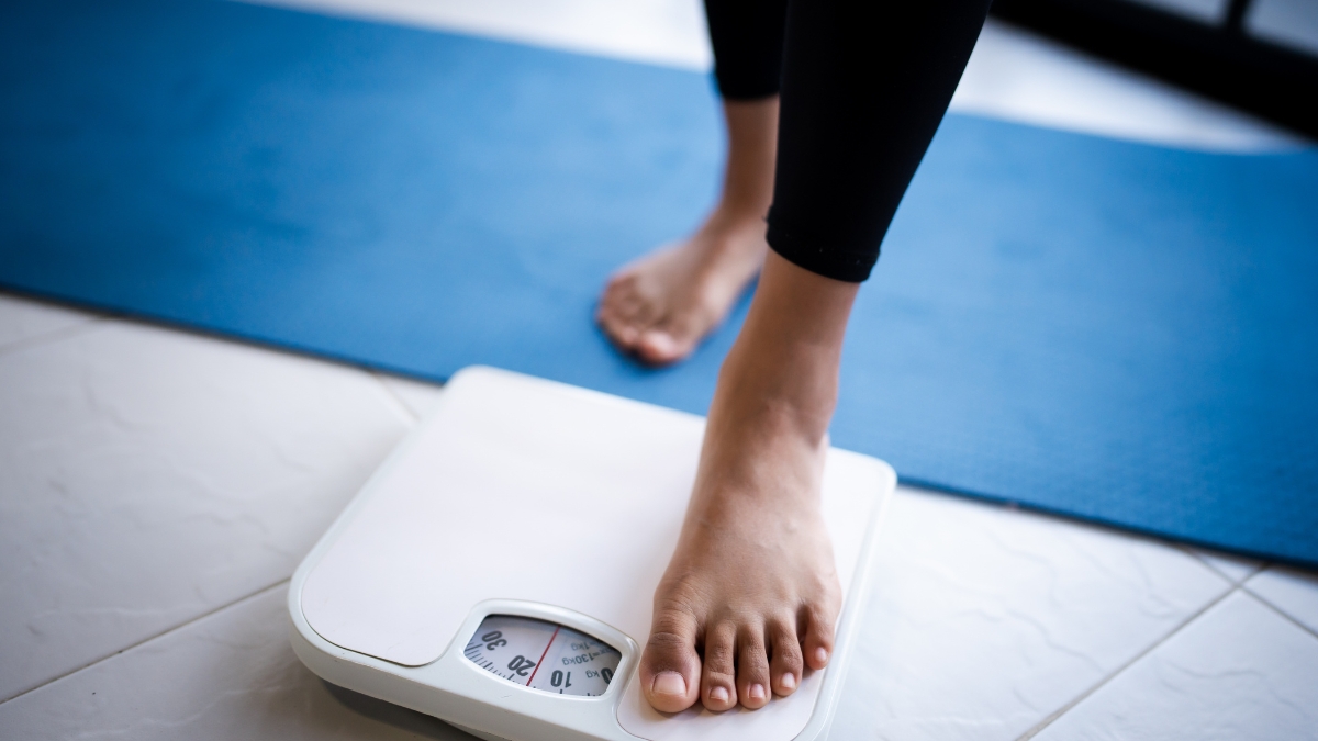 Feet tentatively step onto a scale.