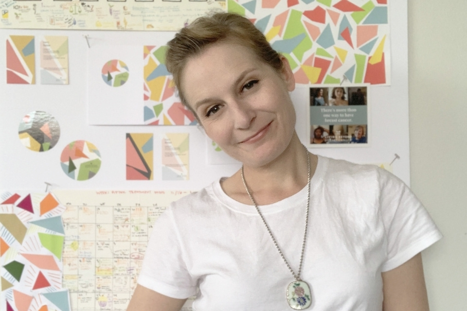 Kerri Besse smiling in front of pages of The Cancer Calendar