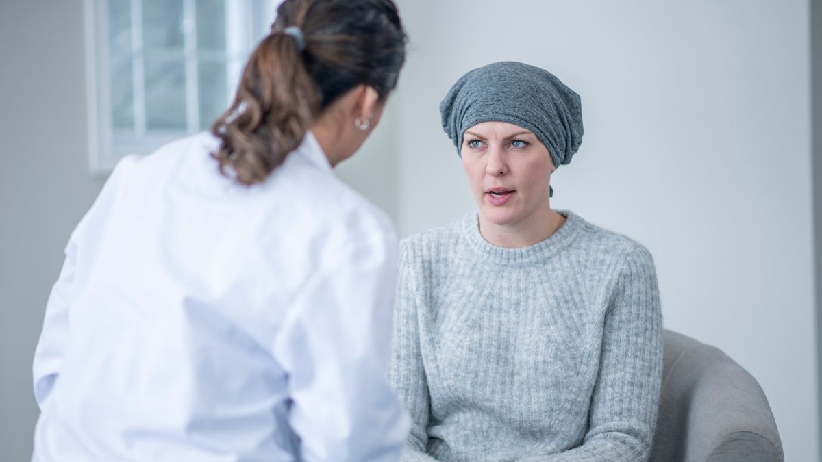 A woman wearing a soft blue headwrap talks candidly with her healthcare provider.