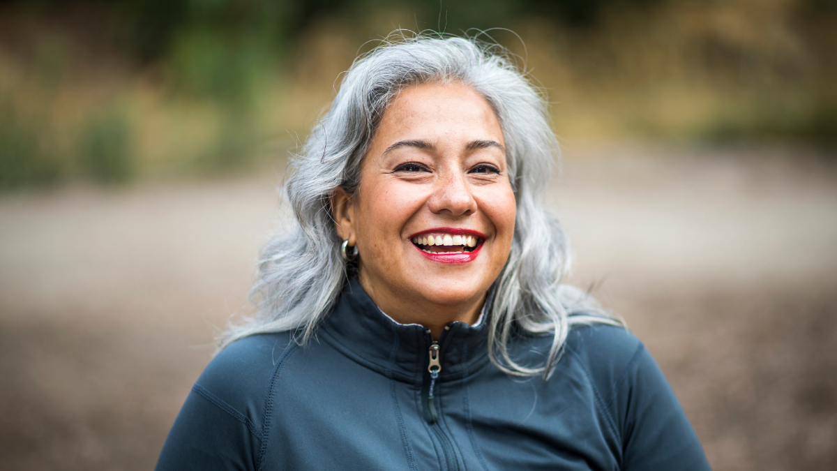 A woman smiling and wearing a bright lip color.