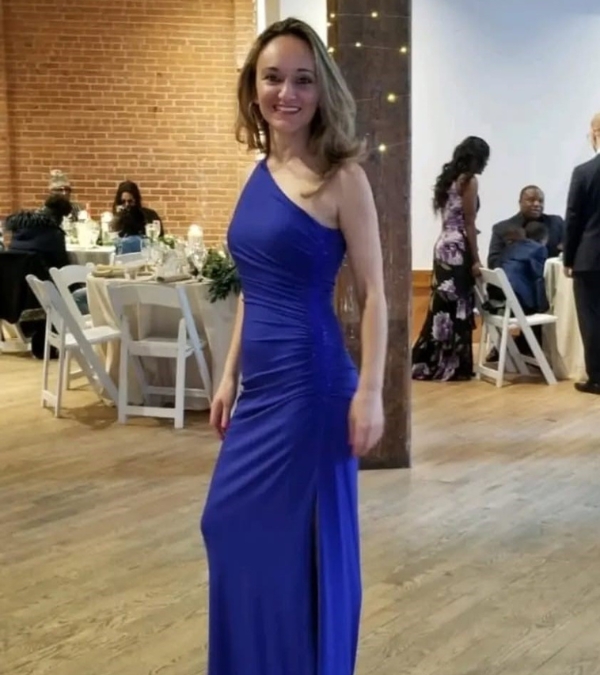 In an image taken before she was diagnosed with breast cancer, Florina Dragovic wears an elegant blue gown to a formal event, party tables and rental chairs behind her.