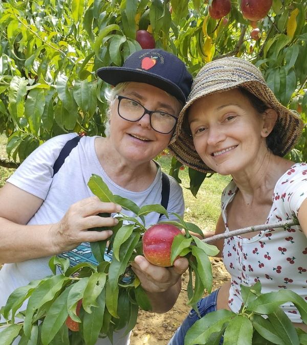 Florina Dragovic and her mom hold up the applies they have picked at an orchard.