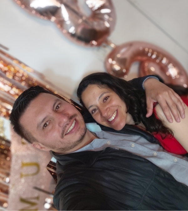 Gynna Quintero and her boyfriend Diego hold each other close in front of glittery party celebrations.