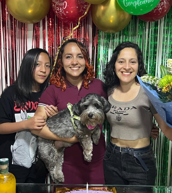 Gynna Quintero and two female family members hold their adorable dog at a family celebration.